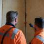 men looking at crack in wall