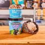 Waffle cone, cup and fresh packed pint in front of Ben & Jerry's ice cream shop menu board.
