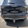 Black Isuzu MU‑X rear view with tow hitch and “#TOWBARJOE” plate, parked outdoors.