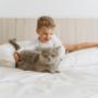 a kid and a cat is playing on the bamboo sheets