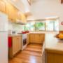 The fully equipped kitchen includes a long meal prep bench, gas cooktop and oven, family size fridge, microwave, dishwasher, toaster, jug, saucepans, fry pans, sandwich grill and cooking utensils.