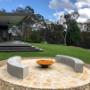 Fire pit and off-form concrete bench seating with sandstone paving.