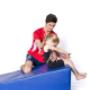 Coach helping gymnast with backward roll