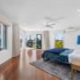 Master bedroom with timber floors, blue bedding, and balcony doors
