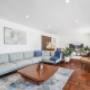 Open-plan living room with sectional sofa, timber floors, and TV