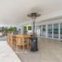 Covered outdoor dining area with timber table, heater, and sliding glass doors