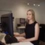A Trekk Gympie team member stands confidently at her desk, focused on her dual-screen setup in a modern and minimal office. The photo captures a moment of quiet productivity and professionalism.