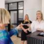 A friendly front-desk exchange at Trekk Gympie. A smiling team member hands paperwork to a client while another team member looks on with a warm welcome—capturing the team’s approachable and service-first mindset.