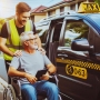 A friendly driver assisting a passenger in a wheelchair into a maxi taxi set in a suburban Brisbane