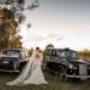 the back of a brides dress in front of vintage wedding cars in the Hunter Valley ben can wedding venue by Thierry Boudan Photography