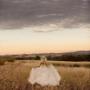 a single bride walking through the long grass watching the sunset in the Hunter Valley bimbadgen estate