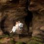 caves beach Bride and Groom having there picture taken sitting on the rocks in the cave photographed by Thierry Boudan Photography