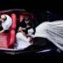 Bride and Groom in vintage wedding car smiling at each other as the veil flows in the background