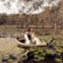 Bride and Groom in the Hunter Valley on there wedding day kissing in a row boat in the a local pond with Lillies floating