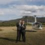 Margan wine broke grooms posing for a photo whilst having some wine with Hunter Valley helicopter in the background by Thierry Boudan Photography