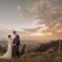wedding couple on the hill in the Hunter Valley smiling with the beautiful view behind them as the sunsets