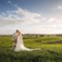 A bride and groom stand together in a picturesque Hunter Valley field, posing for a portrait by Thierry Boudan Photography