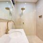 Light-toned bathroom with brass tapware, walk-in shower, and stone benchtop