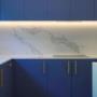 Close-up of marble-look splashback and under-cabinet lighting with blue kitchen cabinetry