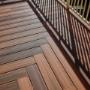 Close-up of timber deck boards with herringbone border and railing shadows