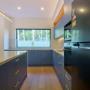U-shaped kitchen with blue drawers, brass handles, and large window
