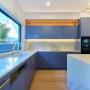 Modern U-shaped kitchen with blue cabinetry, brass hardware, and marble-look splashback in Randwick renovation