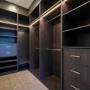 Custom walk-in wardrobe with dark timber joinery, LED strip lighting, and multiple hanging bays