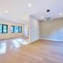 Open-plan living and dining with feature stone wall and modern ring pendant