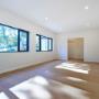 Sunlit living room with wide plank timber floors and black-framed windows