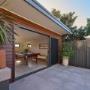 Garden studio with sliding door opening to paved patio and privacy fence
