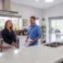 Homeowners talking with a consultant in a bright modern kitchen with a large white island.