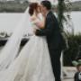 Newlyweds sharing a romantic kiss beneath the veil, surrounded by beautiful florals on their wedding day.